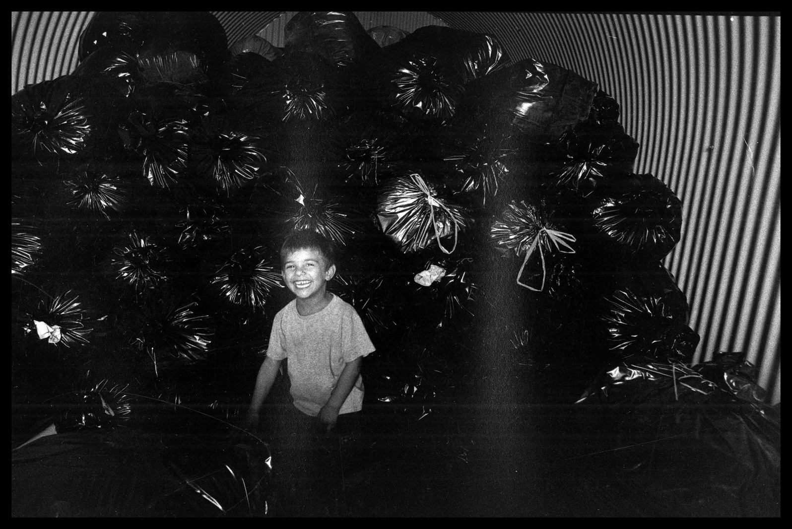 Backo joue devant des sacs de vétements chez Emmaus