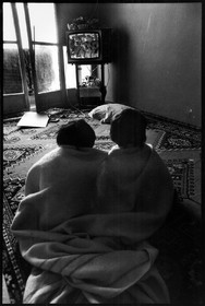 Le fils et le petit-fils de Nasifa devant le poste de télévision retransmettant une séance de débats à l'assemblée nationale. Les objets tels que télévision, tapis, meubles... ont été récupérés chez Emmaüs.